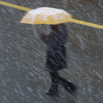 Person im Regen mit gelben Regenschirm